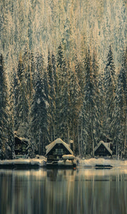 Décoration murale Wandkraft : art mural Winter Wonders 001 : chalets enneigés et sapins au bord d'un lac miroitant, ambiance paisible, couleurs naturelles. Pour un intérieur élégant