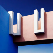 Décoration murale Wandkraft : Mirage in Blue : art mural moderne aux murs roses et bleus, formes en U blanches et détails luxueux, style architectural contemporain. Pour un intérieur élégant