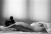 Wandkraft Wanddekoration: Frau mit Haarknoten liegt auf dem Bauch auf einem Bett, stimmungsvoll sanft beleuchtet, moderne Wandkunst in warmen Tönen, beruhigende Ausstrahlung. Für ein stilvolles Interieur
