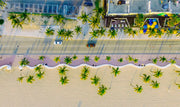 Wandkraft wanddecoratie: Luchtfoto met palmbomen, zandstrand, auto's en terrassen. Zomerse muurkunst in frisse kleuren, Summer Time 021 door Wandkraft. voor een stijlvol interieur