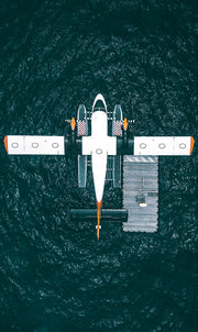 Wandkraft Wanddekoration: Wasserflugzeug mit orangefarbenen Akzenten treibt an einem Steg, moderne Wandkunst Adventure 001 von Wandkraft, frische und abenteuerliche Atmosphäre. für ein stilvolles Interieur