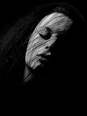 Wandkraft Wanddekoration: Wanddekoration einer Frau mit Schatten auf dem Gesicht, geschlossenen Augen und teilweise bedecktem Haar aus der Gesichter 026 Kollektion. Für ein stilvolles Interieur